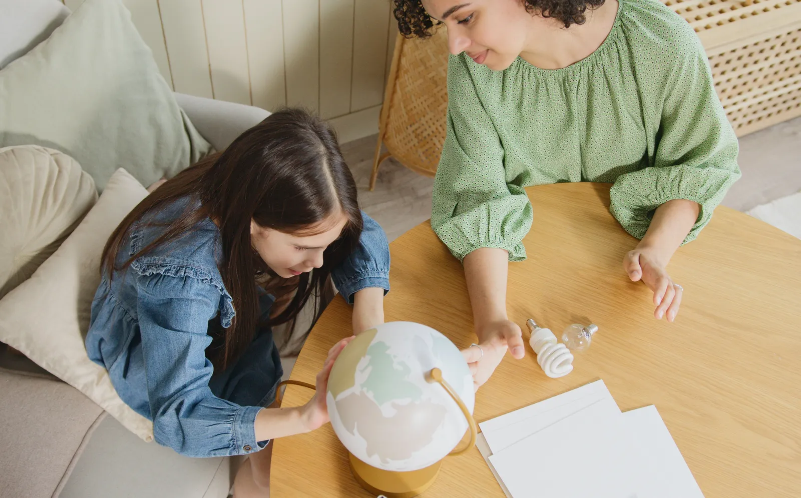 Mother and daughter looking at a globe together at a table at home