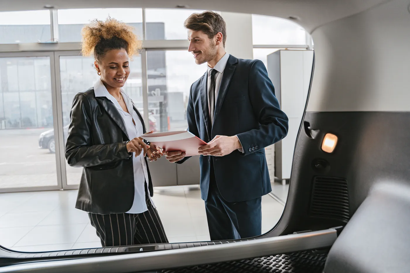 Salesperson going over vehicle options with a customer inside a car dealership showroom