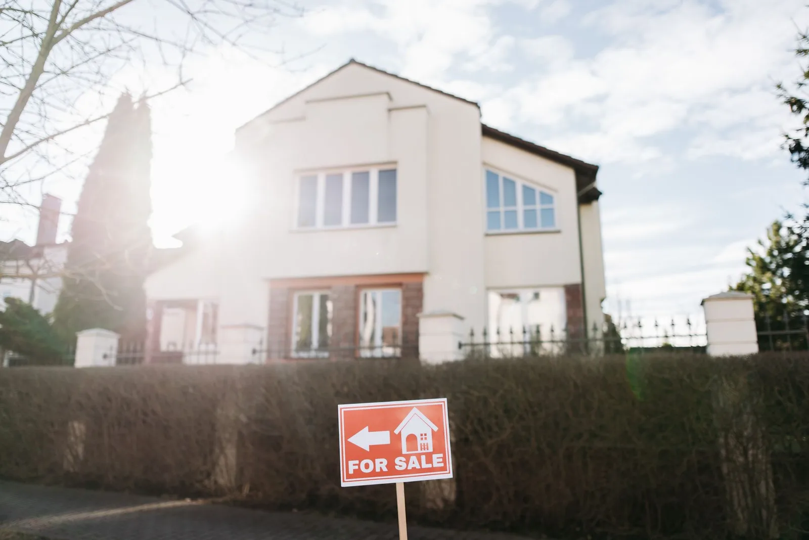 Suburban house exterior with a for sale sign in the front yard