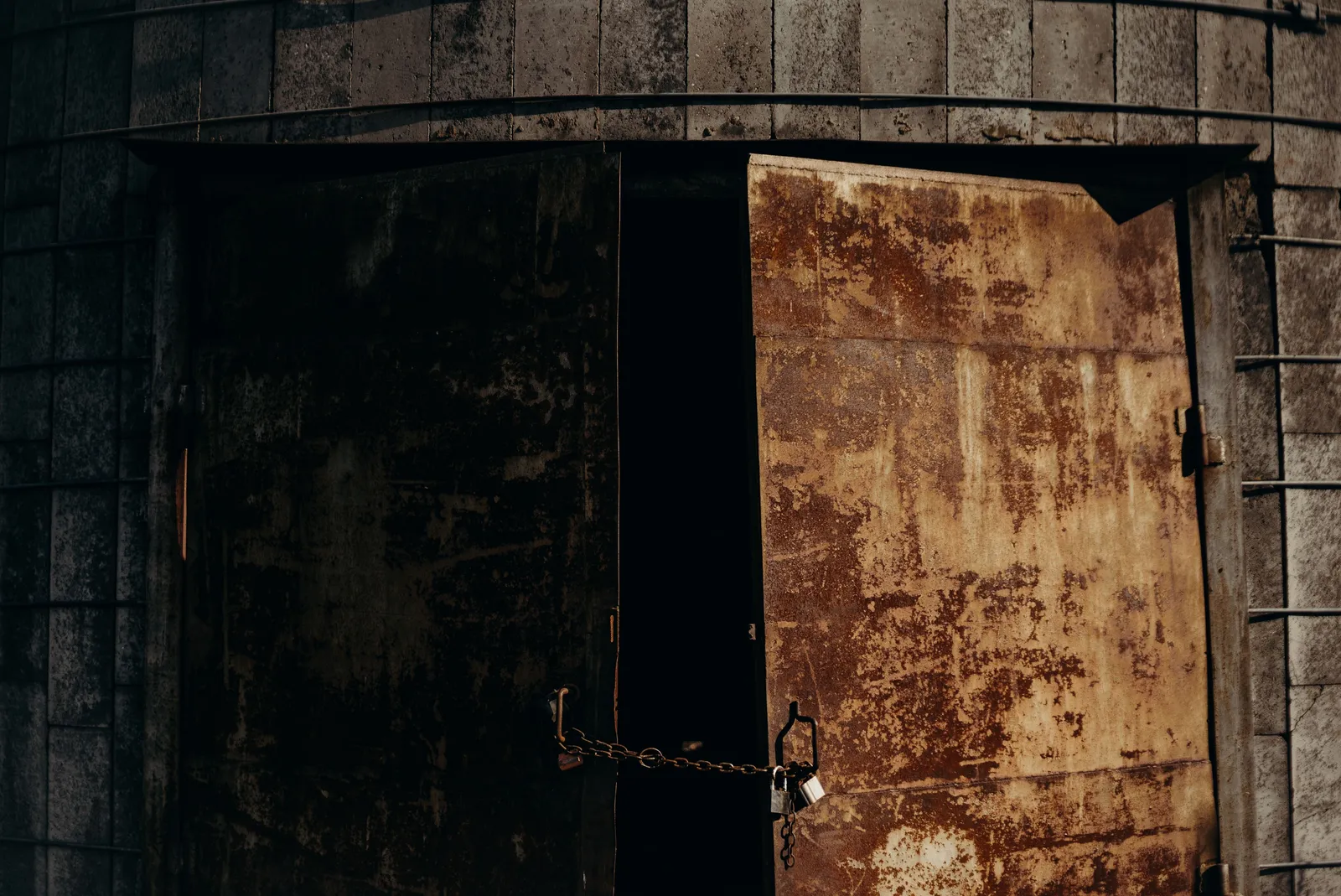 Rusted metal double doors held shut with a chain and padlock
