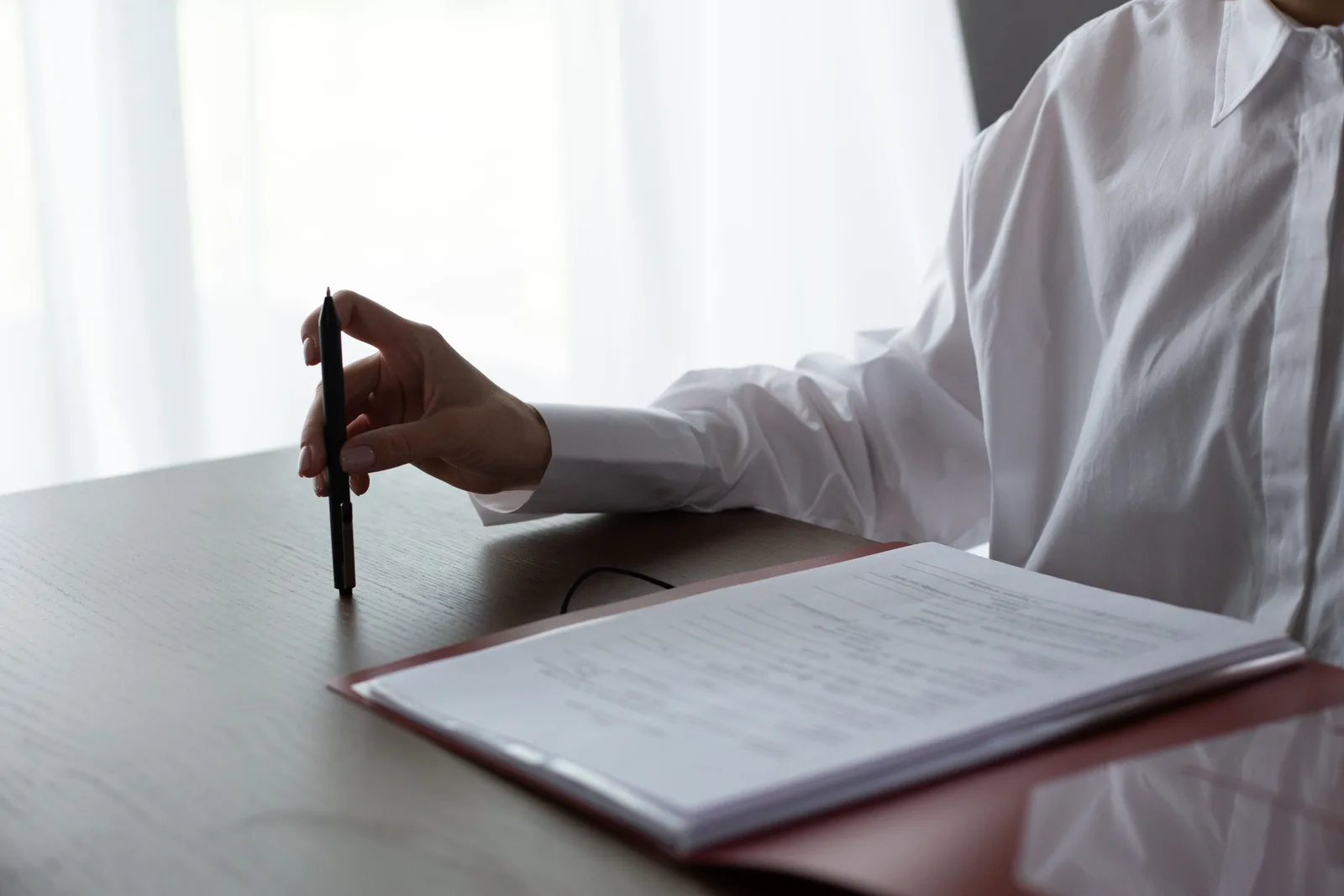 Person examining printed documents with a pen at a table