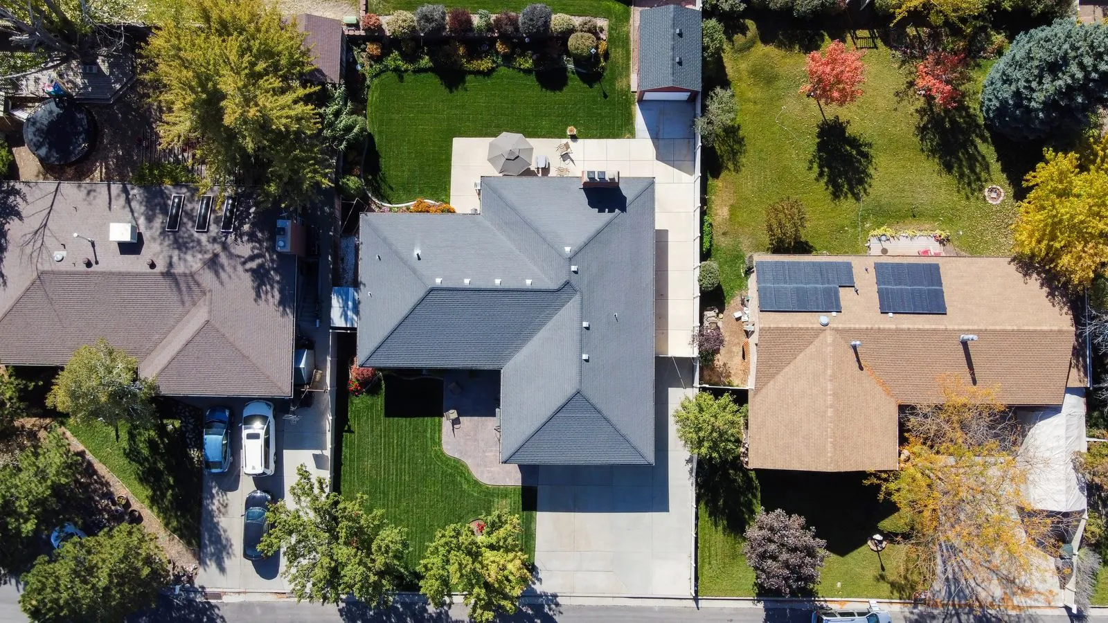 Aerial view of a suburban street in autumn, with solar panels on one house roof among its neighbors