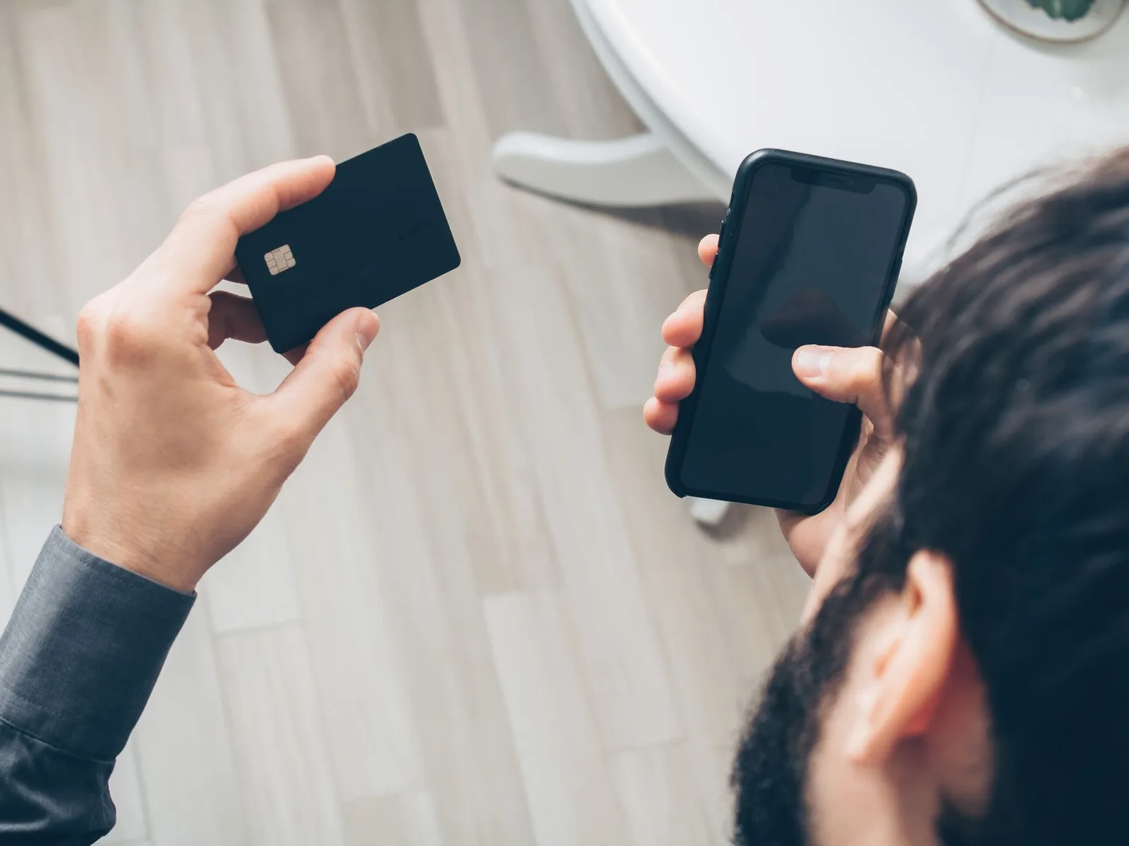 Over the shoulder view of a person holding a plain credit card and a phone