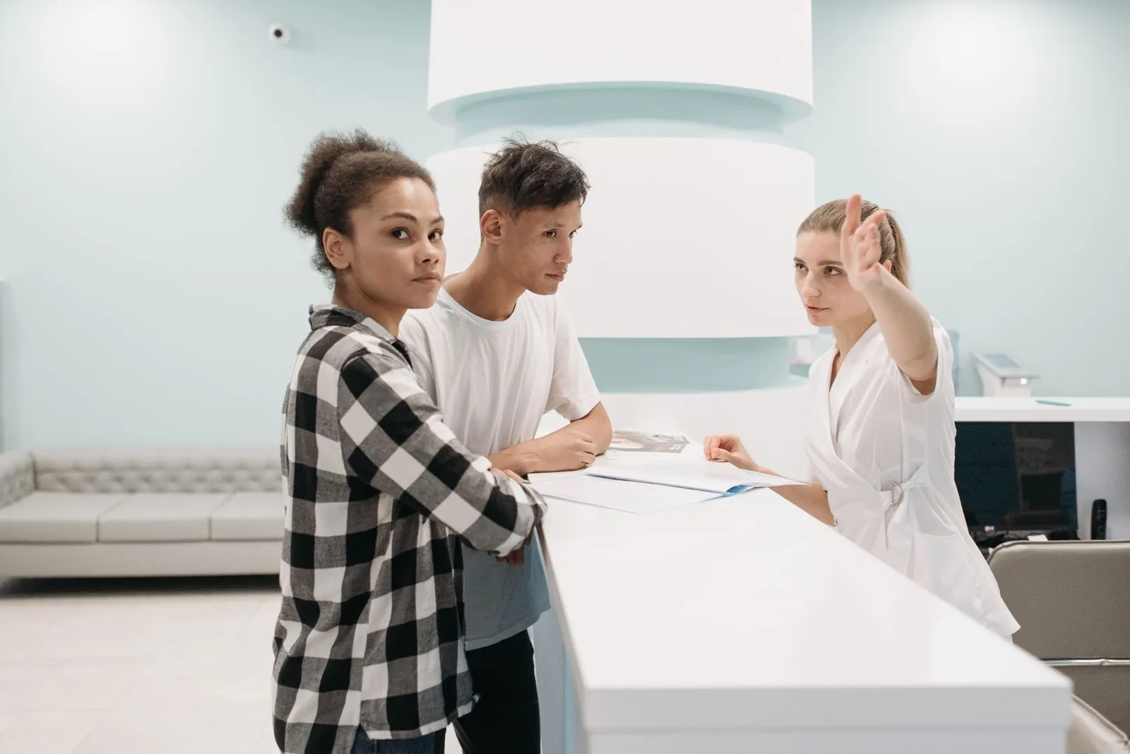 Two people checking in with a receptionist at a clinic registration desk