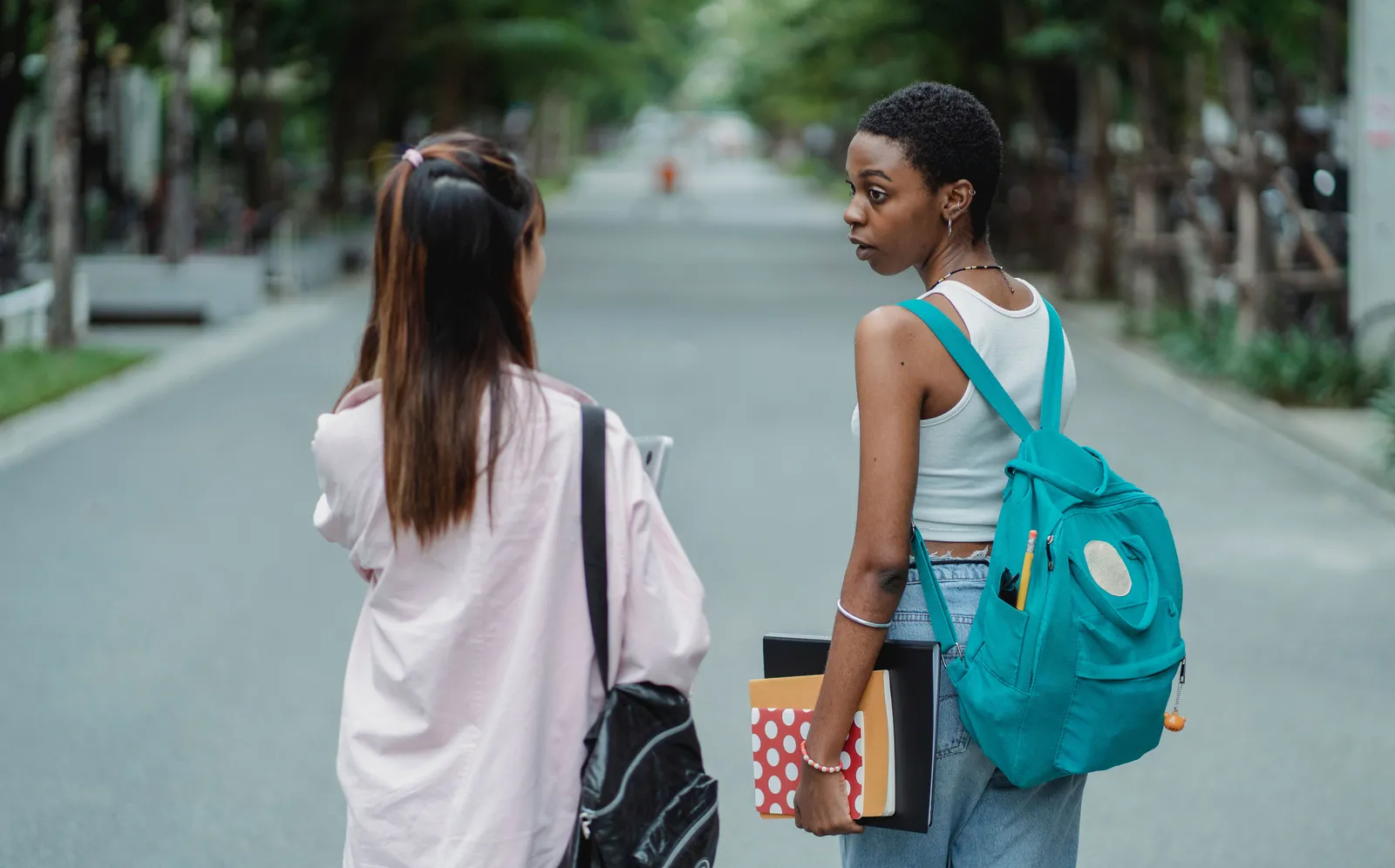 Students walking outdoors carrying backpacks and supplies on the way to class
