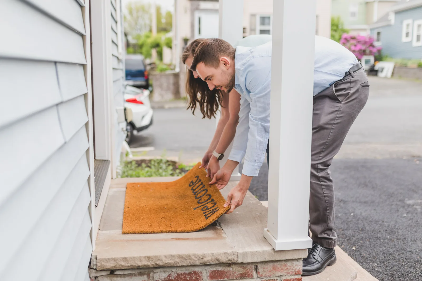 Young couple setting a welcome mat at the front door of their new home