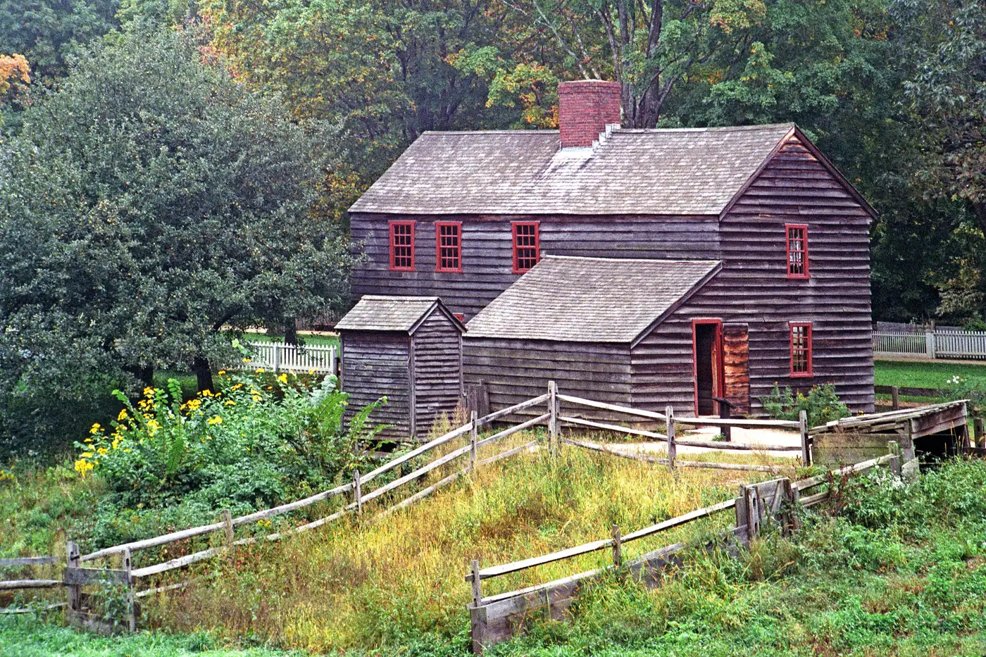Old wooden farmhouse surrounded by trees on a rural property in Vermont