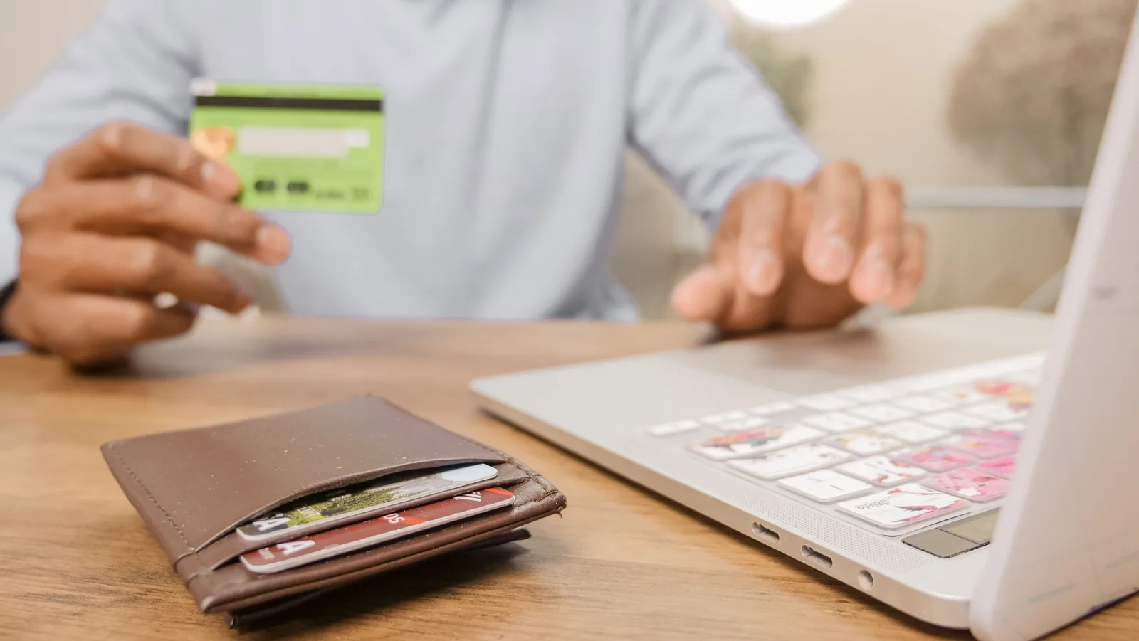 Person holding a bank card while shopping on a laptop at a table