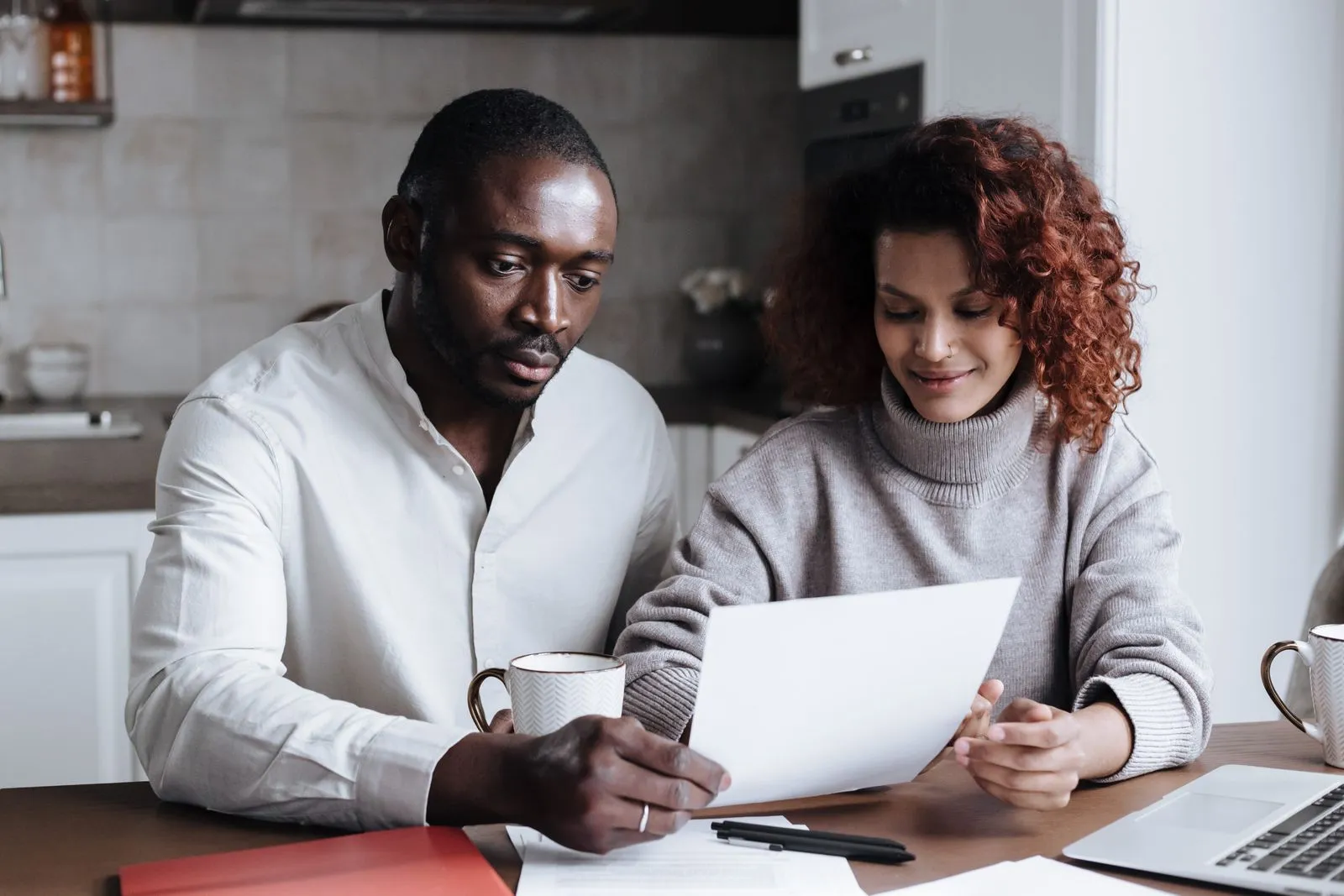 Couple sorting through home closing paperwork at a kitchen table