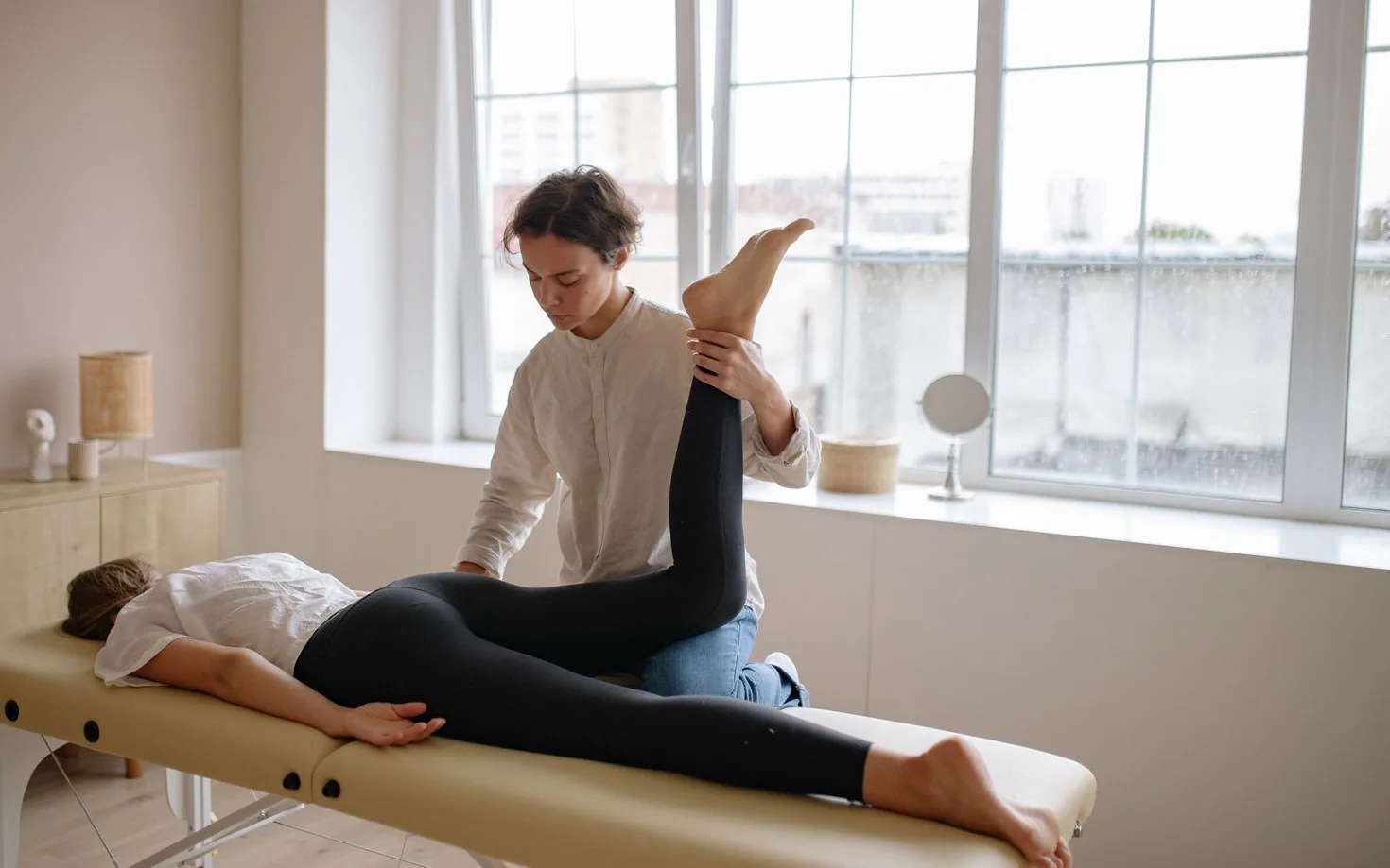 Therapist stretching the leg of a patient lying face down on a treatment table