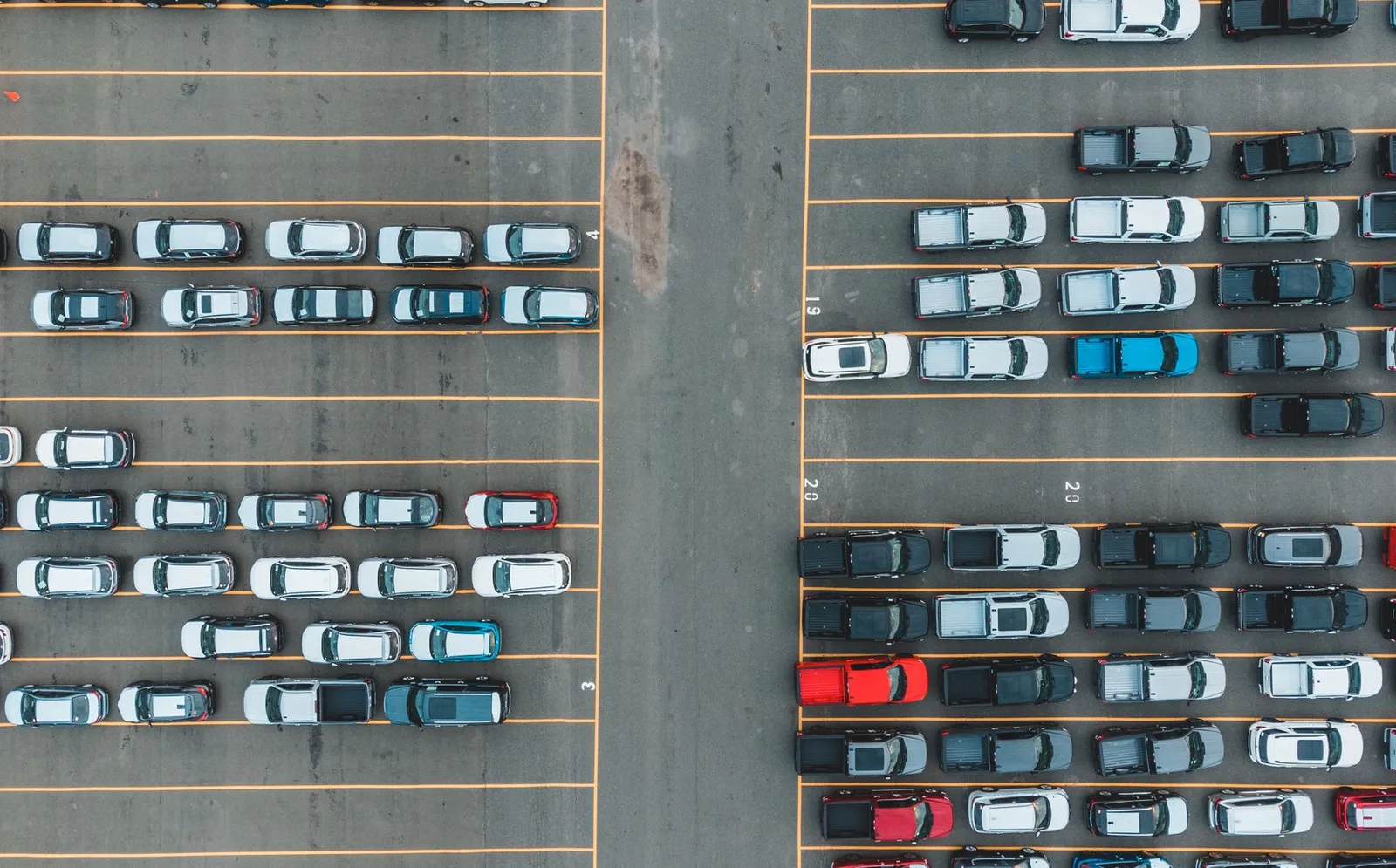 Aerial view of rows of cars and pickup trucks parked in a large lot