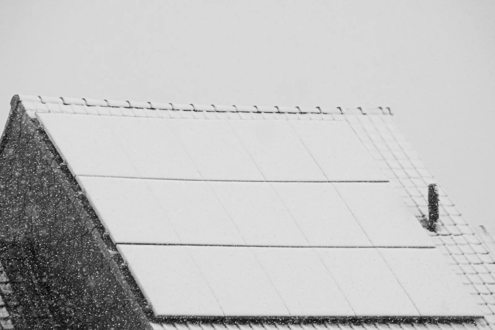 Rooftop solar panels covered in fresh snow during a snowfall