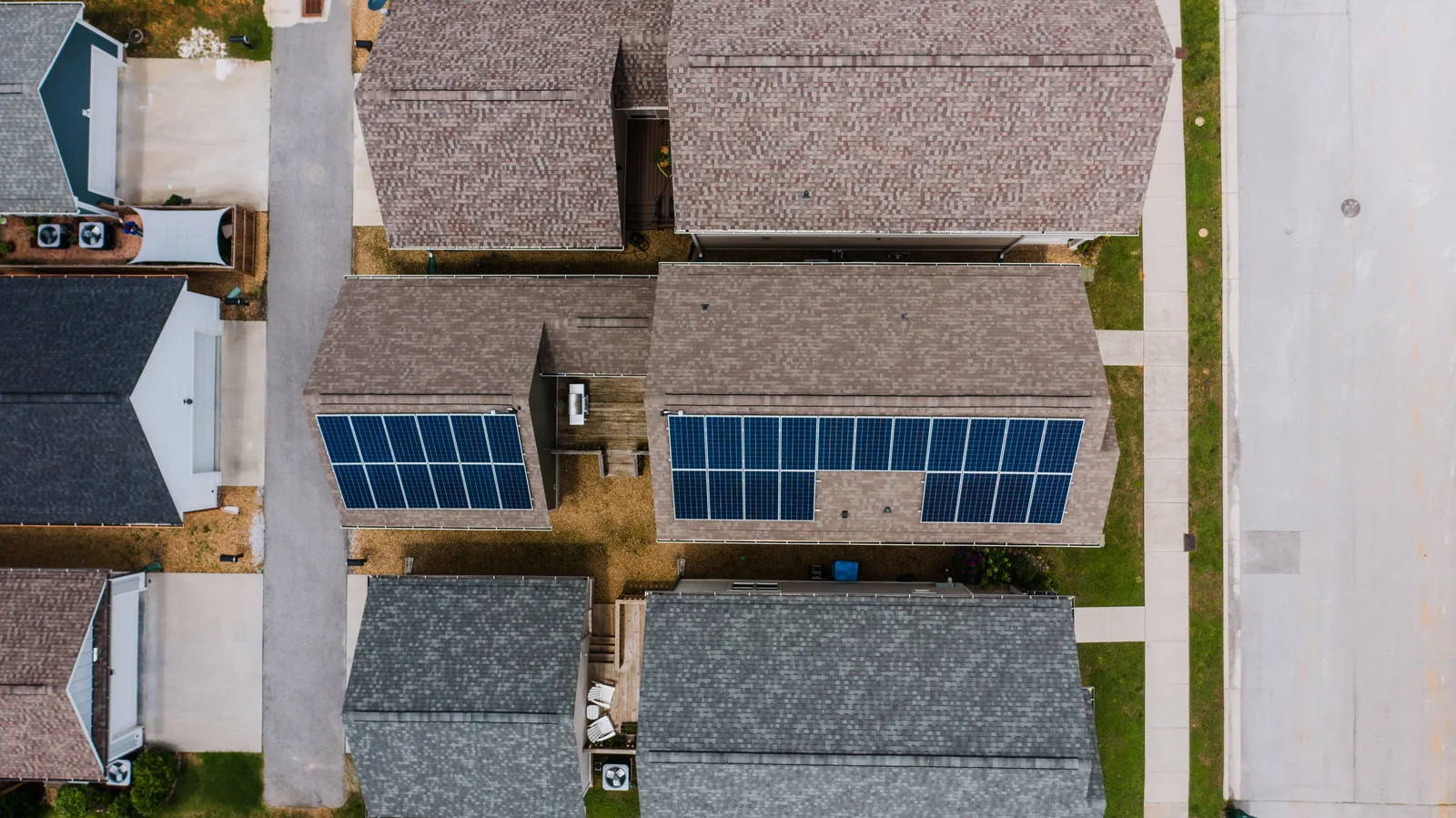 Overhead view of suburban houses, one roof carrying solar panels while the neighbors go without