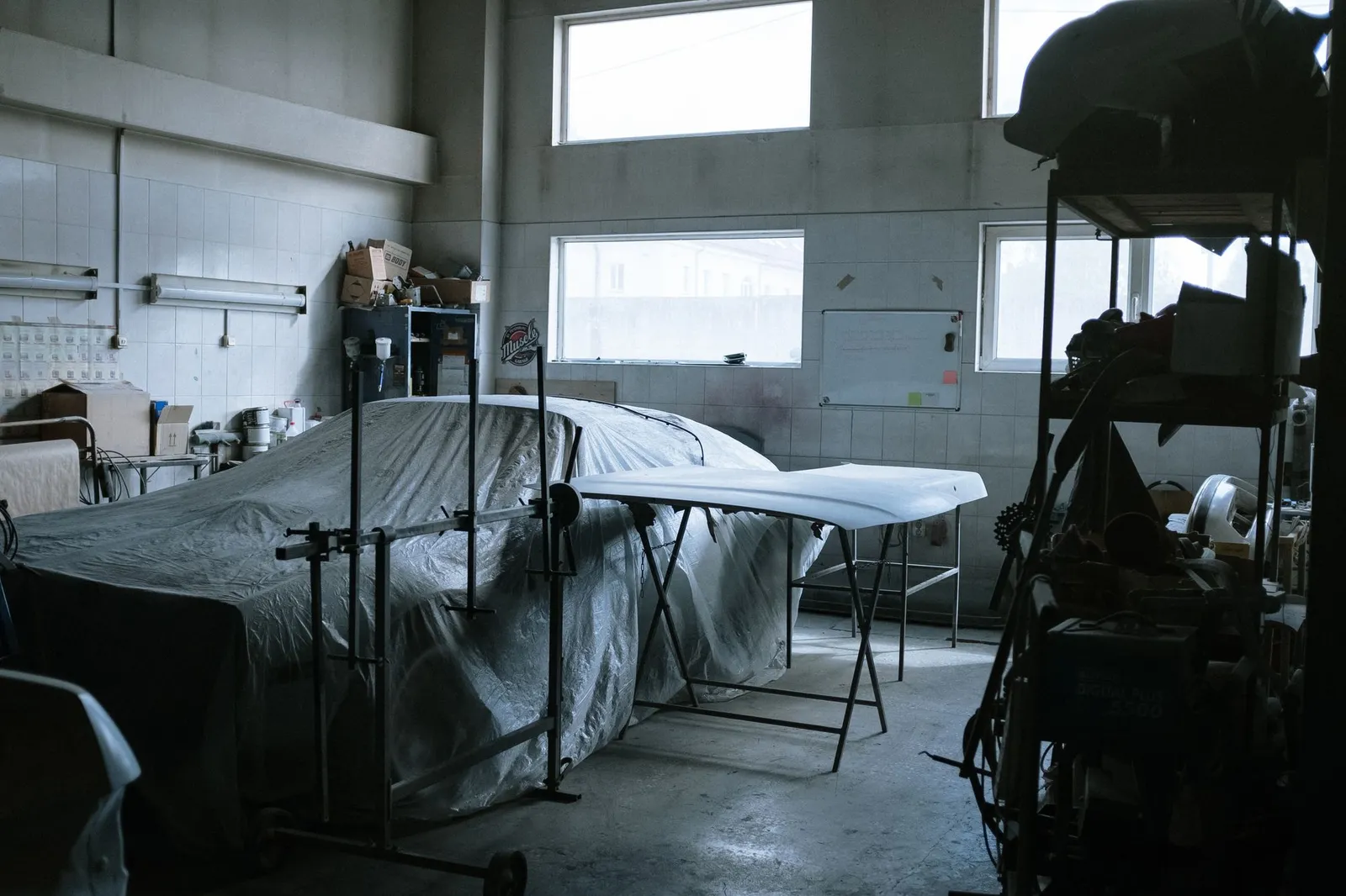 Indoor auto repair shop with a covered car, tools and equipment