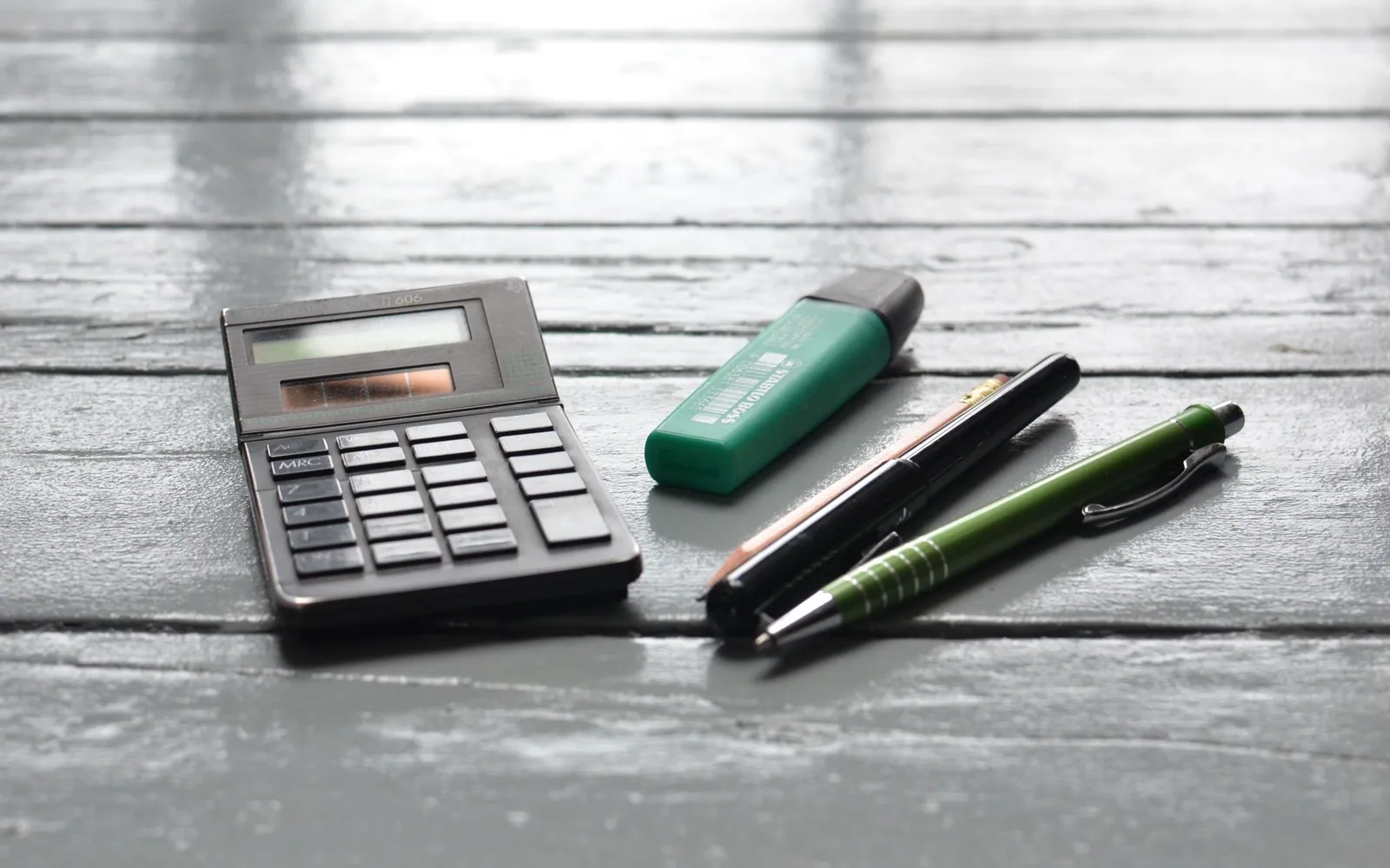 Calculator and pen on a wooden desk