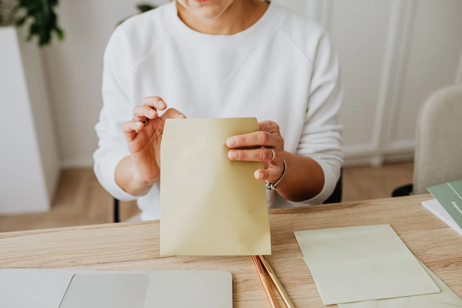 A person at a desk pressing down the flap of a brown paper envelope
