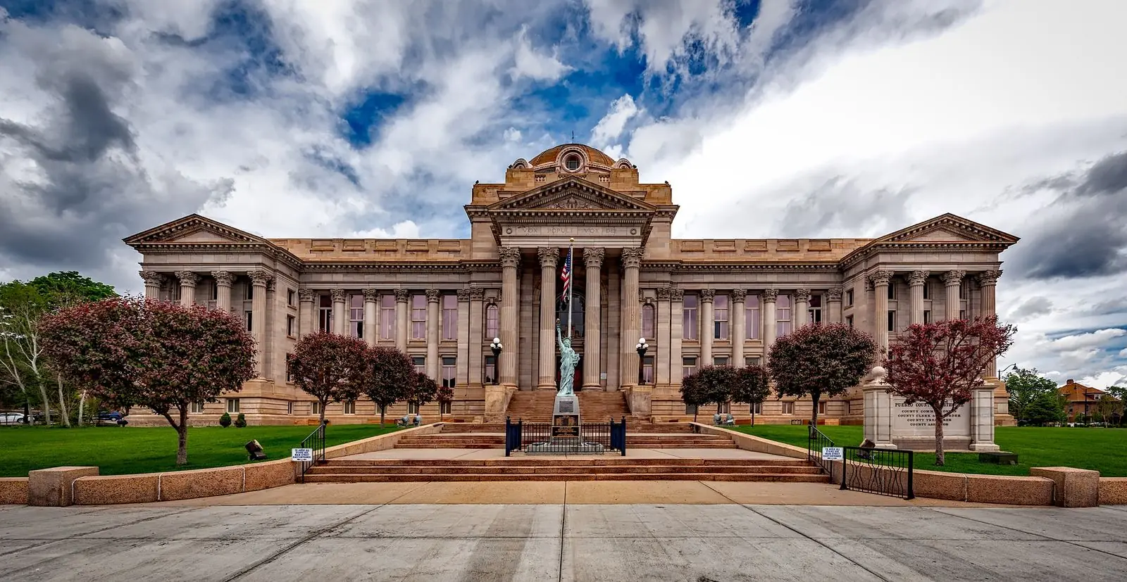The columned stone facade of a county courthouse under a heavy cloudy sky